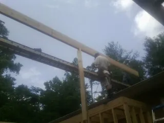 Carpenter setting a ridge beam over a new addition frame — Ice Dam Removal by Roofing Brothers in Locke