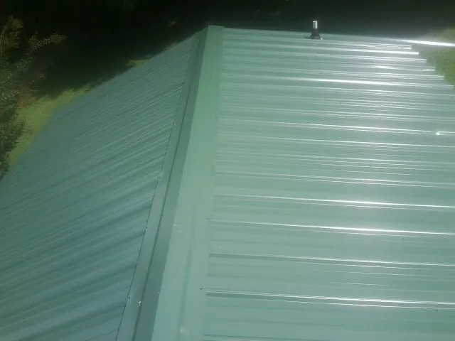 New green metal panels meeting at the ridge of a roof — Flat Roof Repair work by our crew in Locke