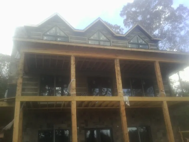 Dormers and porch framing on a large log home under construction — Roof Coating work by our crew in Locke