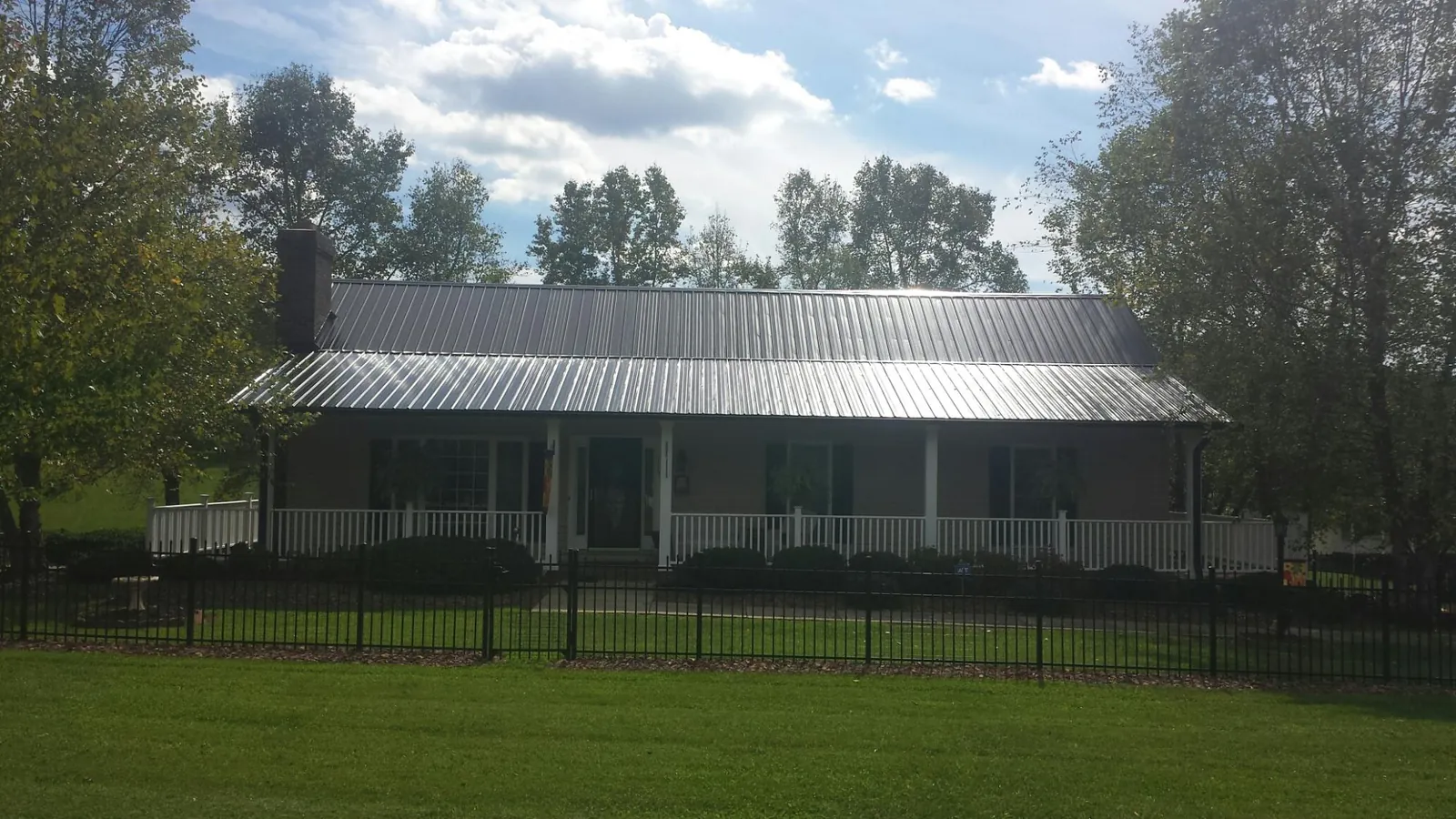 Gray metal roof on a brick ranch with a full width front porch — Gutter Guard Installation work by our crew in Locke