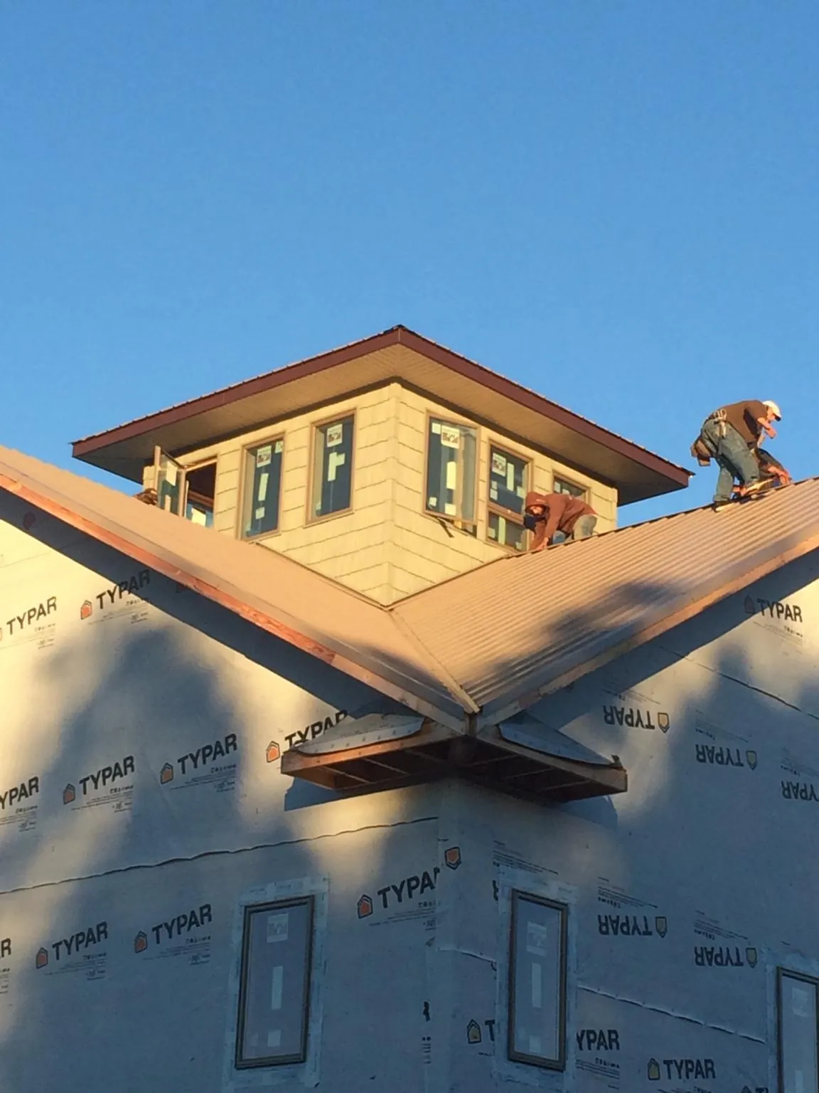 Roofers working around a rooftop cupola on a new metal roof at sunset — Roof Waterproofing in Locke by Roofing Brothers